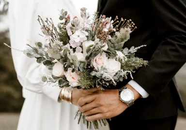 A married couple holding a bouquet of flowers.